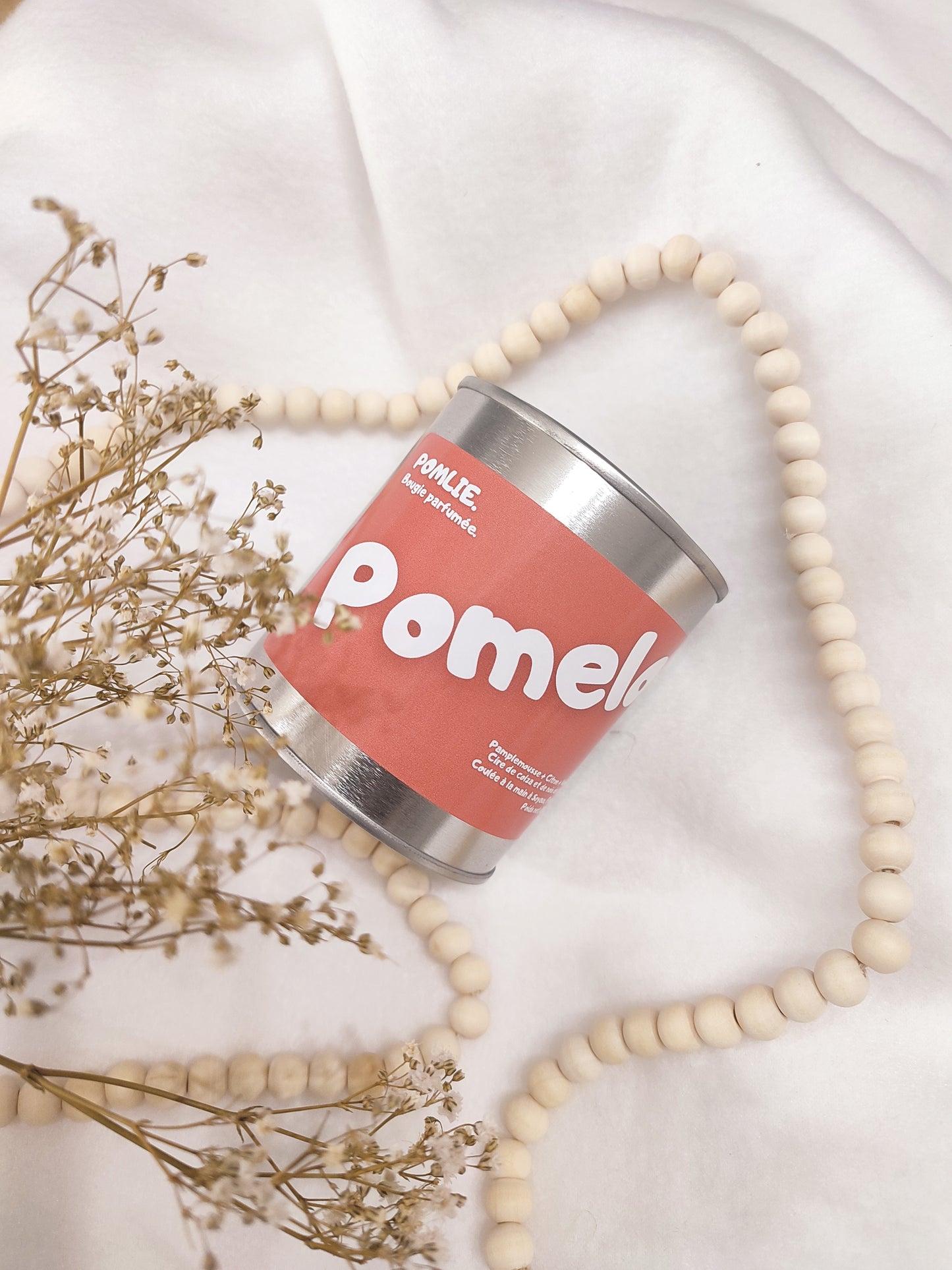 Bougie parfumée Pomelo bleue avec bijoux et fleurs séchées.