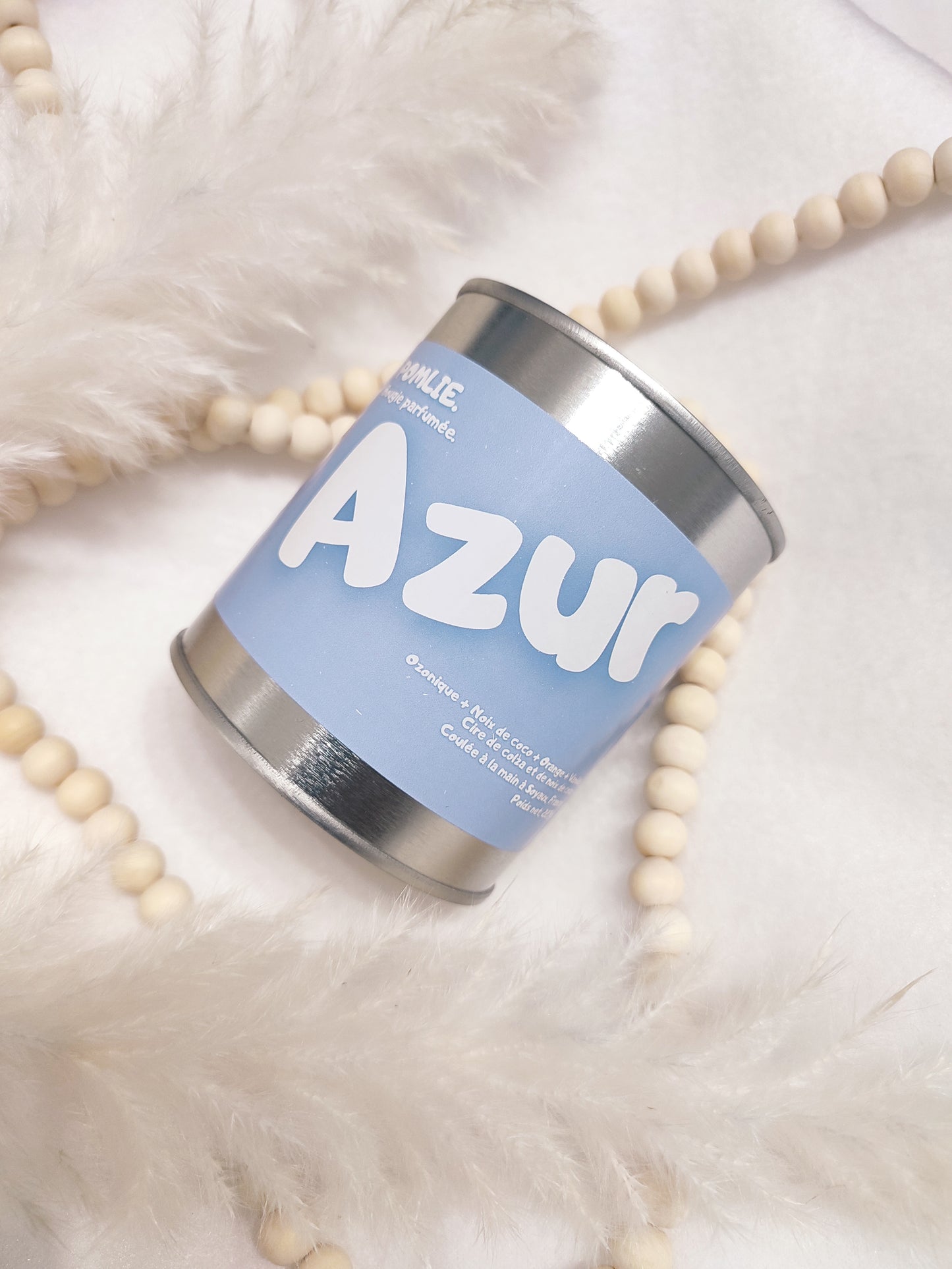 Bougie parfumée Azur bleue avec bijoux et plumes.