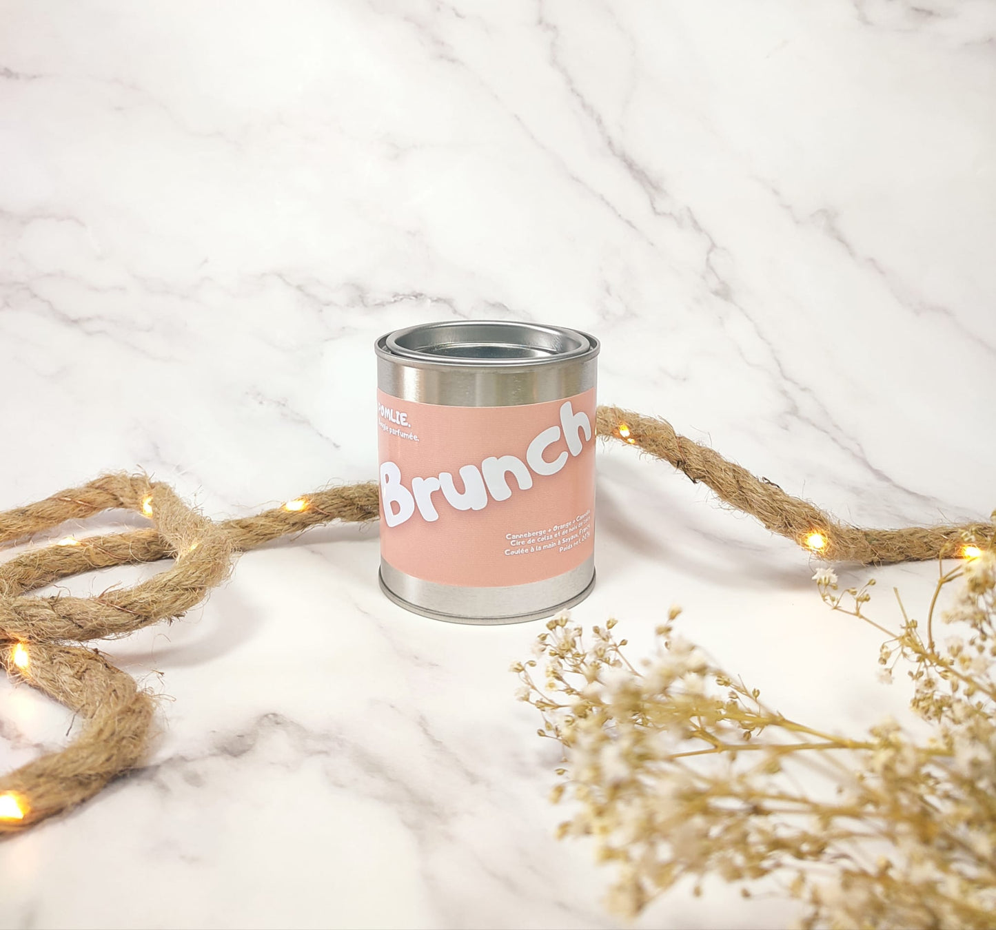 Bougie parfumée Brunch allumée avec corde de décoration et fleurs séchées.