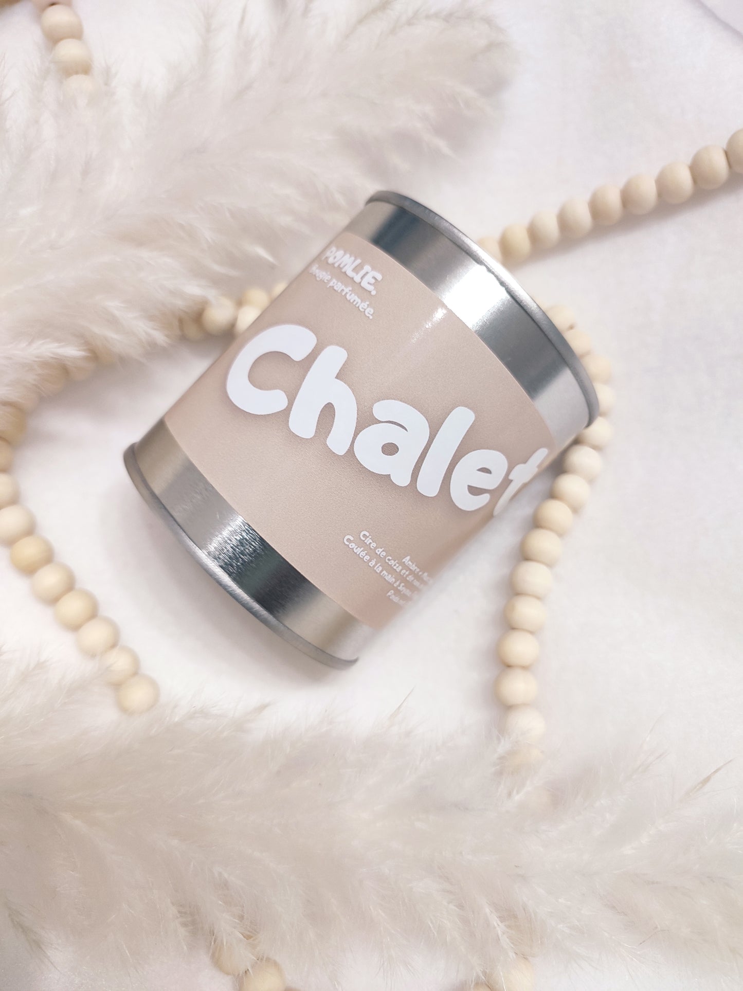 Bougie parfumée Chalet rose avec bijoux et plumes.