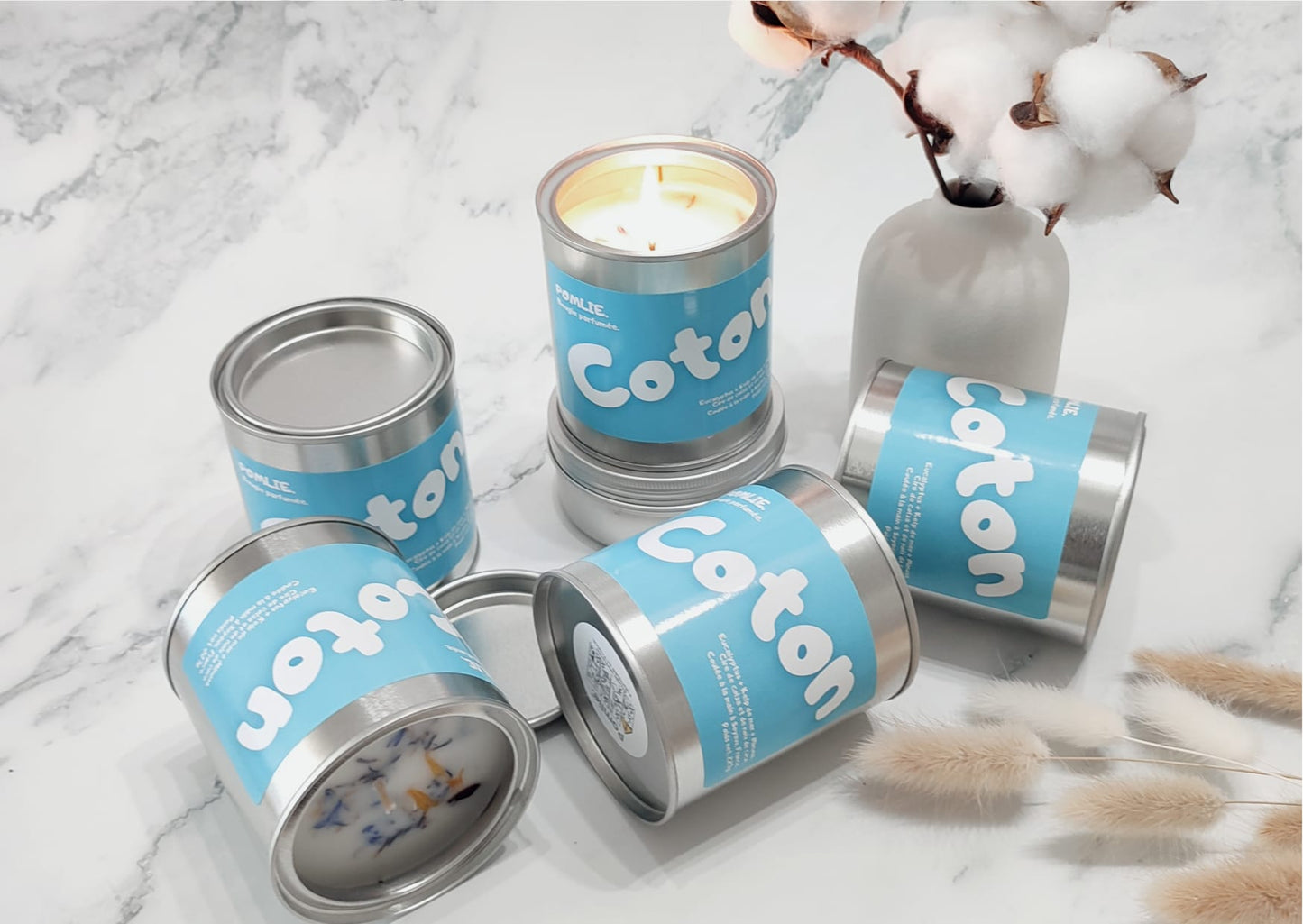 Bougie parfumée Coton allumée avec à ces côtés coton et fleurs séchées.