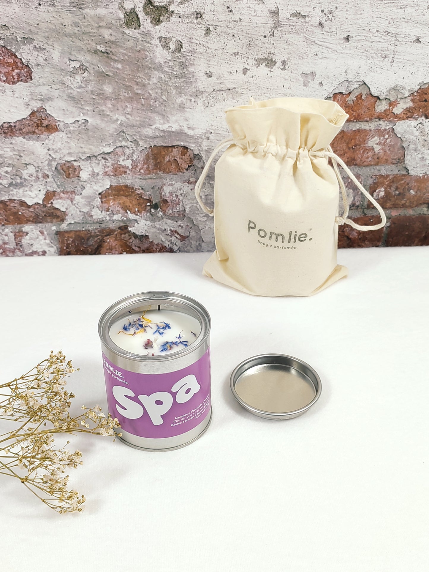 Bougie Pomlie Spa dans une boîte en métal bleu lavande avec sac en coton.