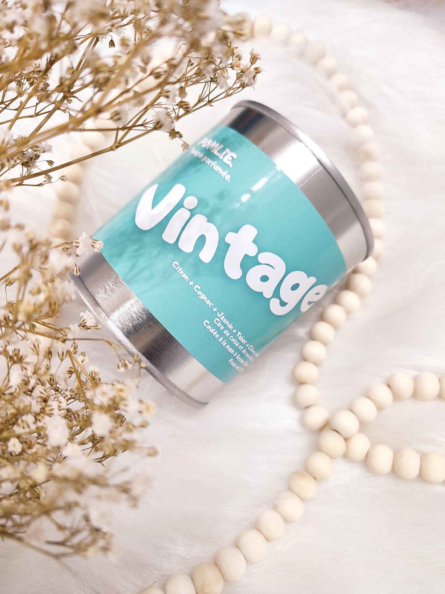 Bougie parfumée Vintage bleue avec bijoux et fleurs séchées.