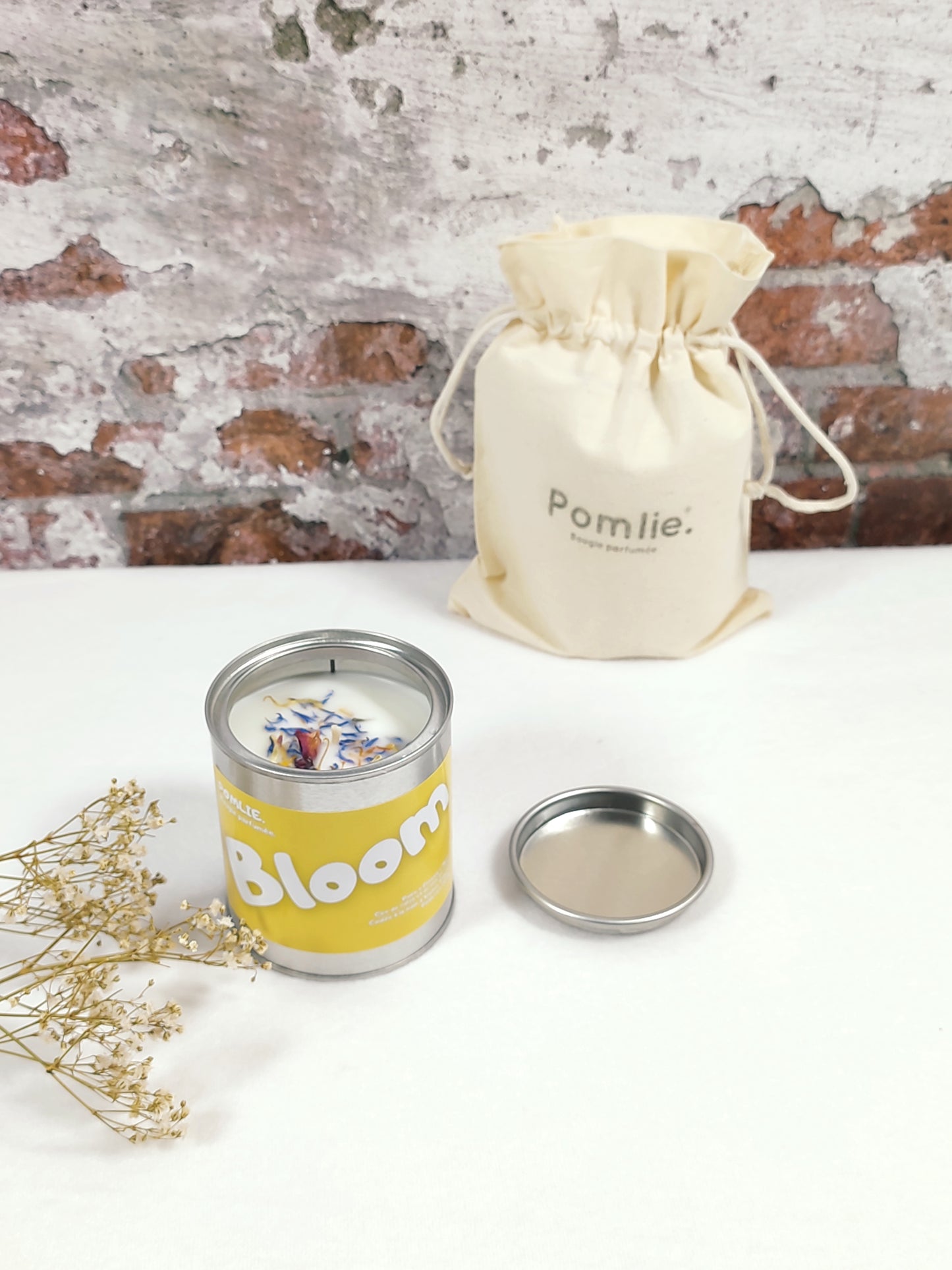 Bougie Pomlie Bloom dans une boîte en métal jaune avec sac en coton.