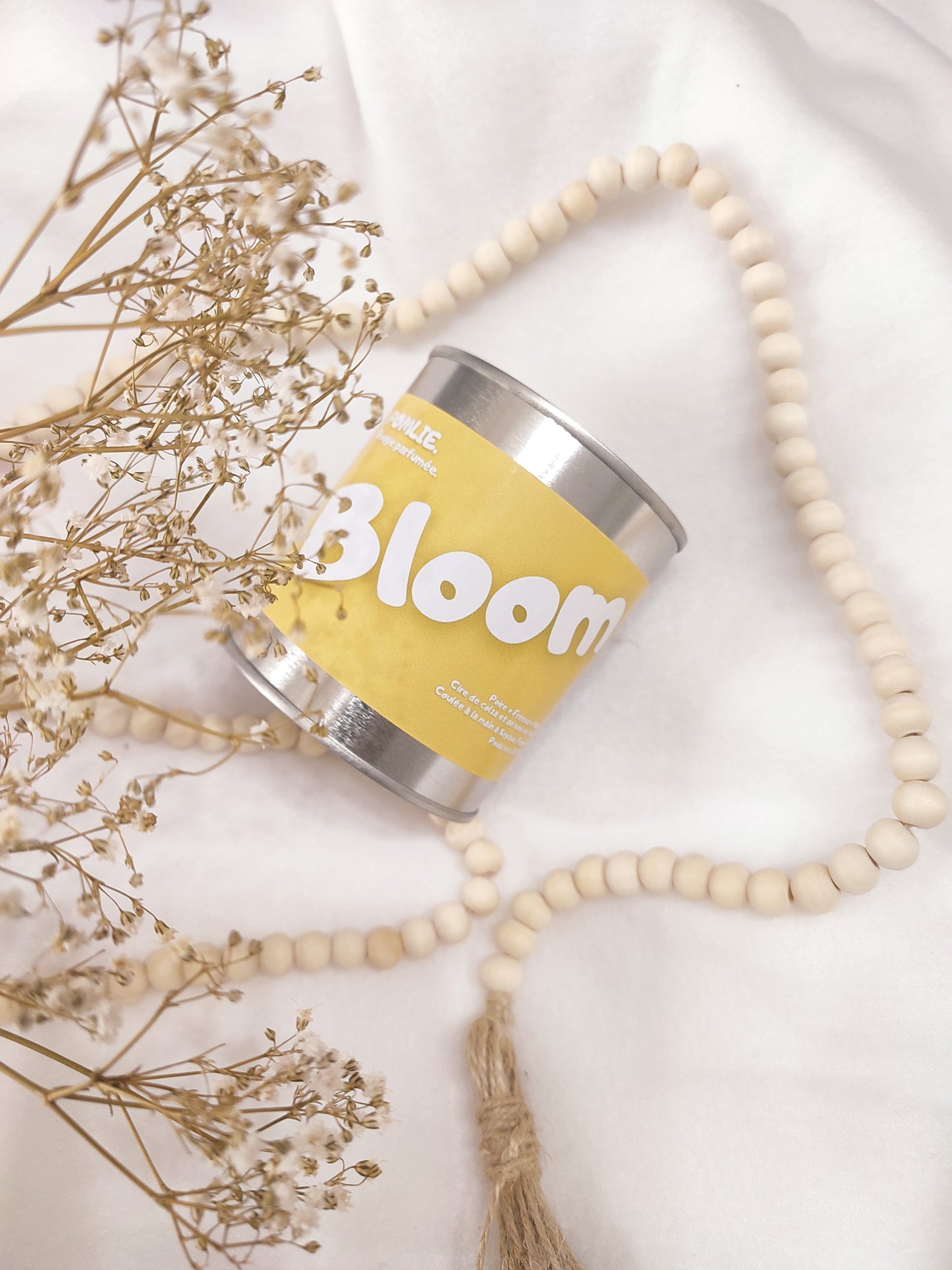 Bougie parfumée Bloom jaune avec bijoux et fleurs séchées.