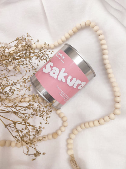 Bougie parfumée Sakura rose avec bijoux et fleurs séchées.